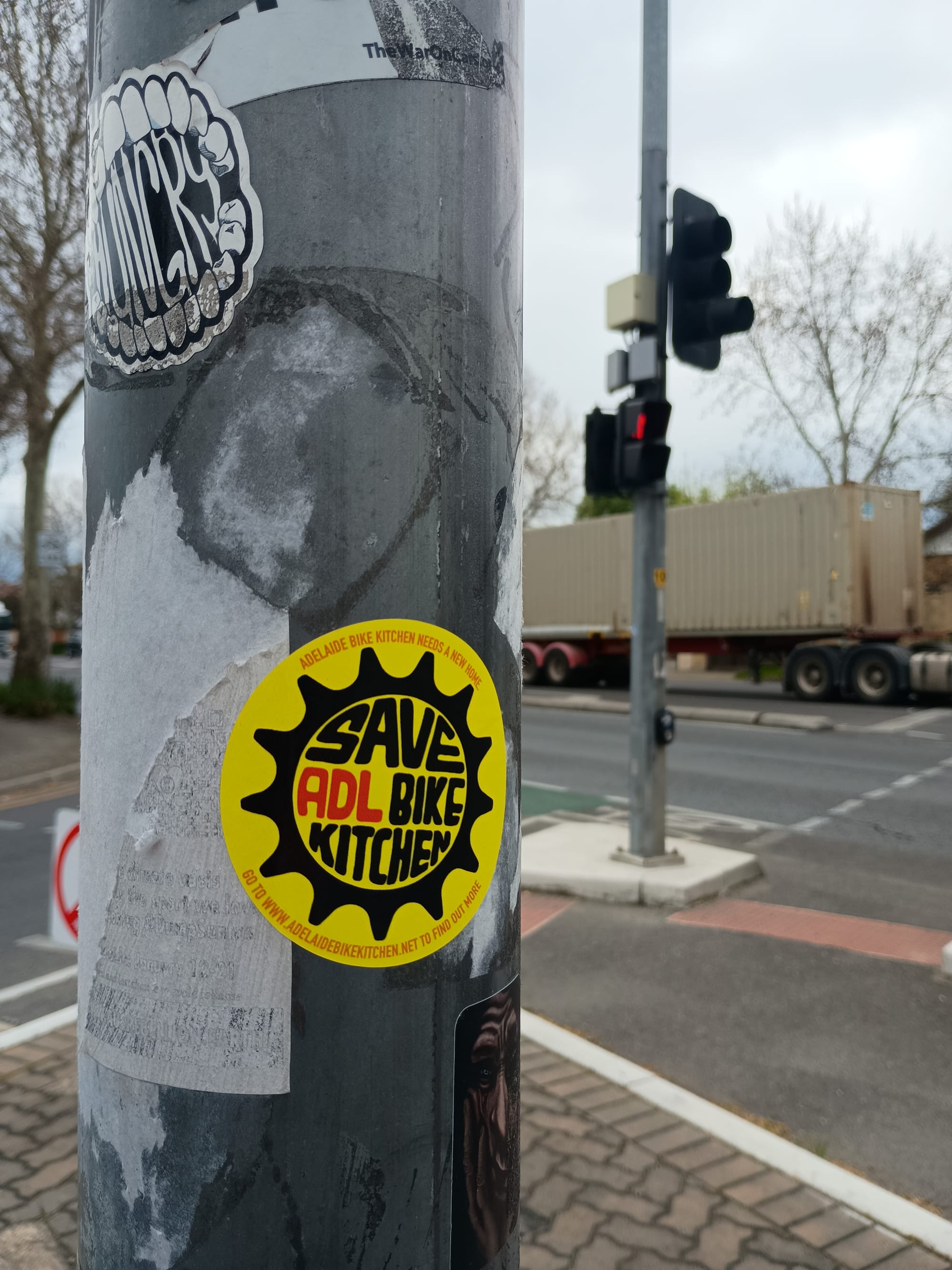 A Saved ADL Bike Kitchen sticker on a pole on the corner of Portrush and Beulah Roads